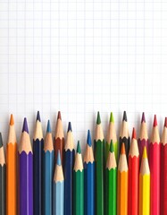 Colorful pencils aligned on grid paper, creating vibrant border against white. Clean, top space perfect for design, art, or educational backgrounds