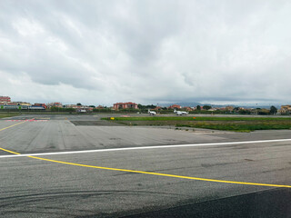 Airportside runway scene with planes on the tarmac, city in distance, and cloudy sky in Poland.