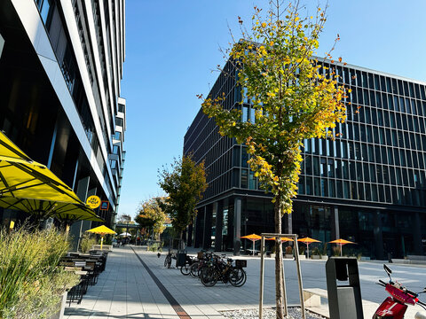 Modern urban plaza with trees and bikes beside glass office BDO Austria GmbH buildings and outdoor cafe in Vienna, Austria.