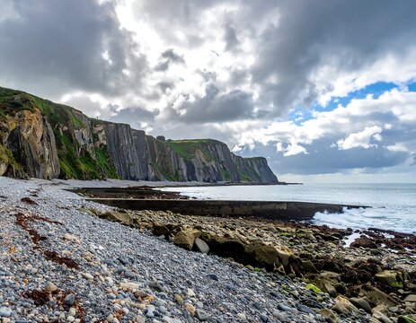 Rocky coastline with dramatic cliffs and cloudy sky - Powered by Adobe