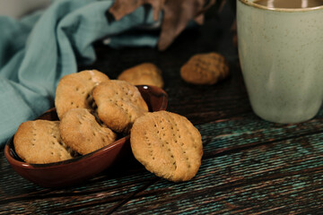 hot drink in blue mug with homemade cookies, dry leaves decoration, fall autumn vibes, rustic cozy seasonal mood