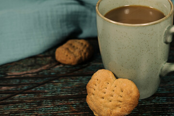 hot drink in blue mug with homemade cookies, heart shaped bisquit, dry leaves decoration, fall autumn vibes, rustic cozy seasonal mood