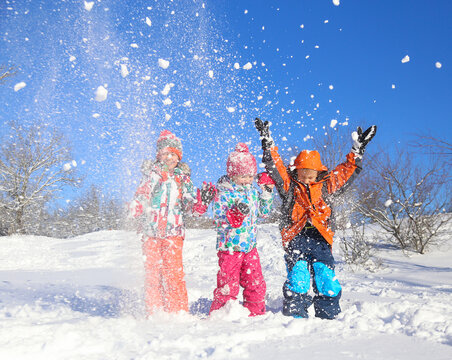 Group of children playing on snow in winter time