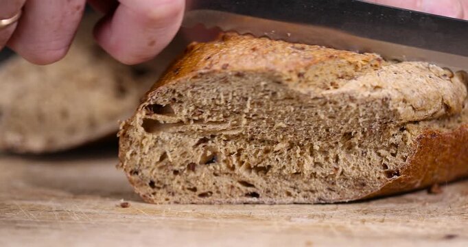 a sliced loaf of rye flour bread lies on the table on a cutting board, a small elongated loaf of freshly baked rye bread on an old cutting board while slicing bread