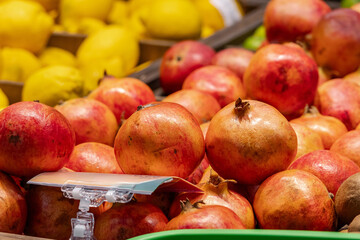 Ripe pomegranates on the market counter. Delicious seasonal fruit. Vitamins and health rfom the nature in the season of colds. Close-up.