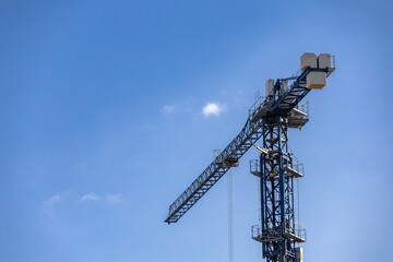 Fototapeta premium Large cranes in construction. An image of a tower crane against the background of a house under construction.