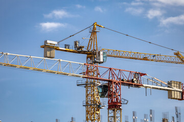 Large cranes in construction. An image of a tower crane against the background of a house under construction.