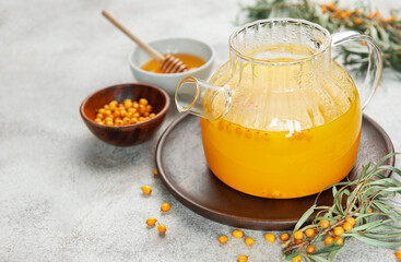 Sea buckthorn hot drink in glass teapot on wooden tray