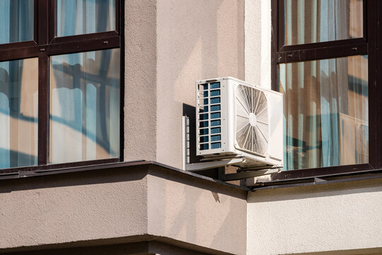 Heating and air conditioning system external units on grass in a house backyard. Air conditioning outdoor unit compressor install outside the building.