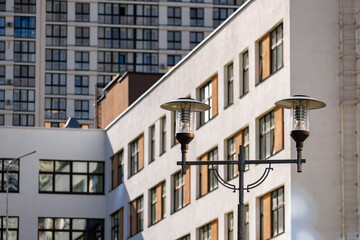 Obraz premium A polished granite sphere decorates a stone post in an urban park. A vintage-style street lamp and green trees complete the elegant architectural setting.