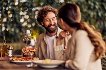 Smiling Couple Sharing Romantic Dinner With Wine at Outdoor Cosy Restaurant