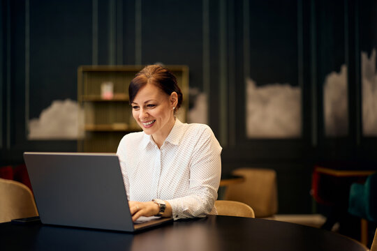 Fototapeta Smiling Woman Working on Laptop in Stylish Office Setting