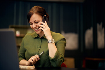 Happy Businesswoman Talking on Phone While Working at Her Office Desk