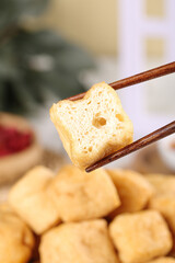Delicious fried tofu puffs with chopsticks showing hollow airy texture - Asian cooking ingredient