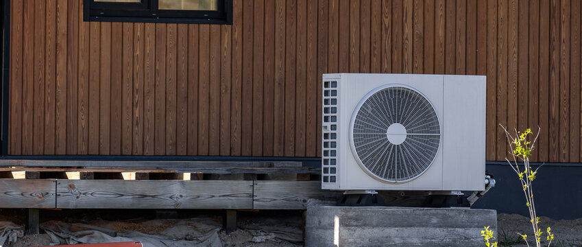 Air conditioning system in a modern frame house. Air conditioner compressor installed on the wall of a building, along with industrial air conditioning units and ventilation systems. Cooling systems.