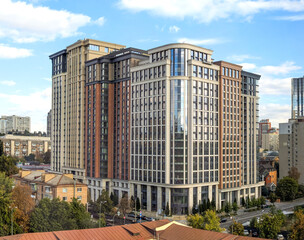 A colonial-style office building with austere steel and concrete architecture. Residential buildings in European city with reflective glass facades, modern high-rise tower.