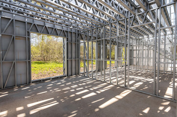 New technology steel frame for construction. Metal frame of the building with a sandwich panel of insulation on the wall. Construction of a new industrial building.