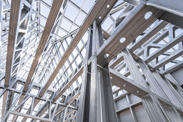 Obraz premium New technology steel frame for construction. New home under construction using steel frames against cloudy sky