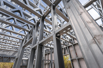 Fototapeta premium Structure of steel roof frame for building construction on sky background.
