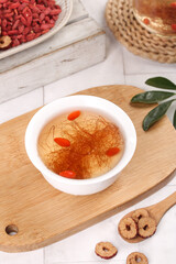 Cornhusk herbal tea infusion with dried goji berries for health and wellness on rustic wooden cutting board