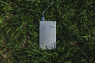 Silver Power Bank Charging on Green Grass in Outdoor Natural Environment