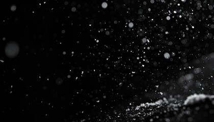 Abstract, monochrome image of particles suspended in air, softly illuminated from an angle, creating bokeh and depth against a dark background