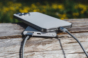Outdoor Charging: smartphone and power bank on a rustic wooden log in nature.