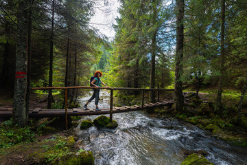 Obraz premium Active woman crossing bridge over Ponor creek