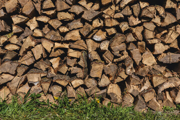 Stacked Firewood Pile Outdoors with Natural Grass and Sunlight