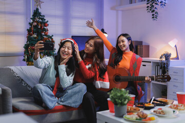 Young women celebrating christmas holiday taking selfie on couch