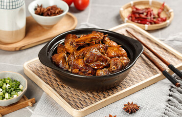 Hot marinated goose meat in iron pot with chopsticks and spices on wooden table - traditional Asian cuisine