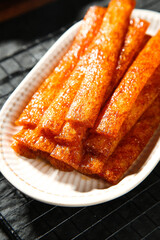 Spicy Wei Long Handmade Orange Glazed Sticks Traditional Asian Snack Food in White Bowl