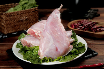 Fresh Raw Rabbit Foreleg Meat Display with Sichuan Peppers and Vegetables on Wooden Table