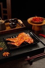 Grilled Rabbit Legs with Asian Glaze and Traditional Seasonings on Black Serving Plate