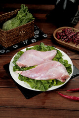 Raw Rabbit Foreleg Meat with Fresh Lettuce and Sichuan Spices on Wooden Kitchen Table