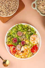 Nutritious quinoa salad bowl with mixed vegetables and quinoa grains on pink background