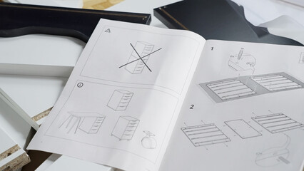 Pile of just unpacked elements and instructions of a new cabinet furniture ready for assembling