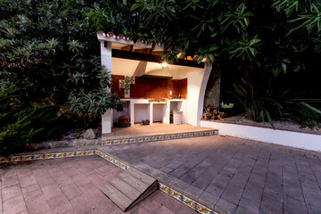 Evening view of a Mediterranean-style villa across an illuminated pool and green lawn.