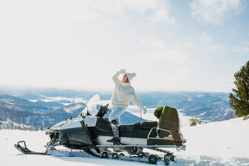 A woman in winter in the mountains on a snowmobile with a beautiful view