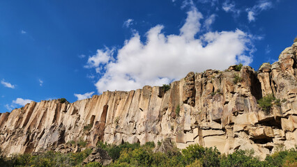 Fototapeta premium Carved over millennia by Melendiz Stream, the rocky cliffs in Ihlara Valley offer hikers a spectacular mix of natural beauty and historical wonders of early Christian churches carved in