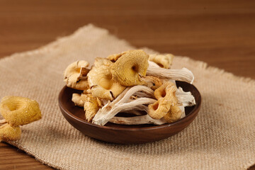 Dried Golden Chanterelle and Elm Mushrooms from Yunnan in Wooden Bowl on Natural Burlap Background