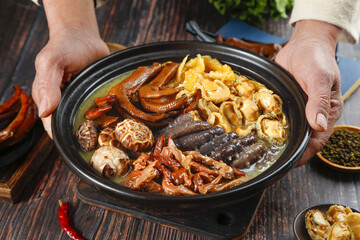 Traditional Chinese Hot Pot with Sea Cucumber and Premium Ingredients Served in Black Ceramic Bowl