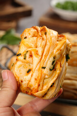 Golden Flaky Layered Pastry Bread with Herbs Held in Hands - Artisanal Handmade Baked Goods