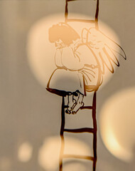 The little angel is sitting on the ladder.