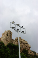 Spotlight pole with rocky cliff and cloudy sky background