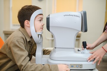 Obraz premium Boy undergoing eyesight examination with autorefractor in ophthalmology clinic