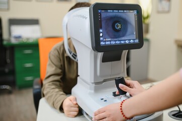Ophthalmologist examining child's vision with autorefractor in clinic