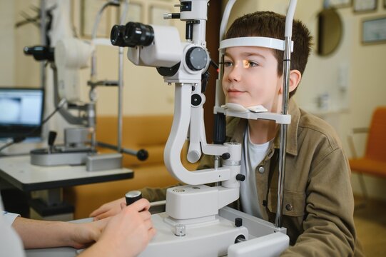 Boy undergoing vision diagnostics with slit lamp in ophthalmology clinic