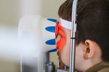 Child undergoing vision diagnostics with modern equipment in ophthalmology clinic