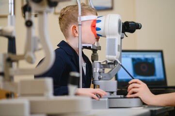 Child undergoing eyesight examination with ophthalmological equipment in clinic